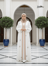 White Embroidered Abaya 🤍 A0002 worn by a woman in an elegant setting with floral embroidery and a neutral hijab.
