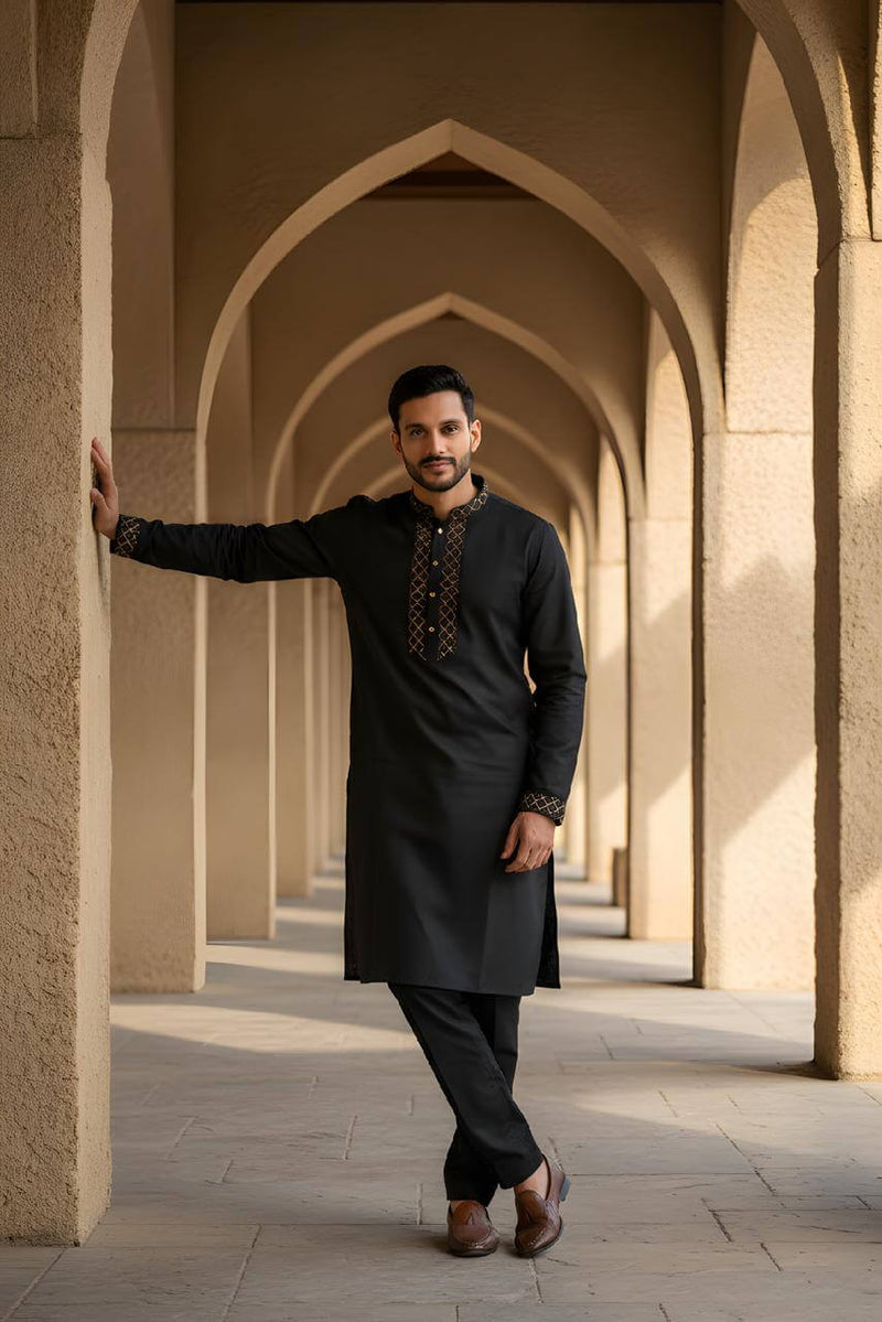Classic Black Bangladeshi Panjabi with Elegant Golden Embroidery P0002 worn by a man standing in an architectural backdrop.