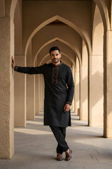 Classic Black Bangladeshi Panjabi with Elegant Golden Embroidery P0002 worn by a man standing in an architectural backdrop.